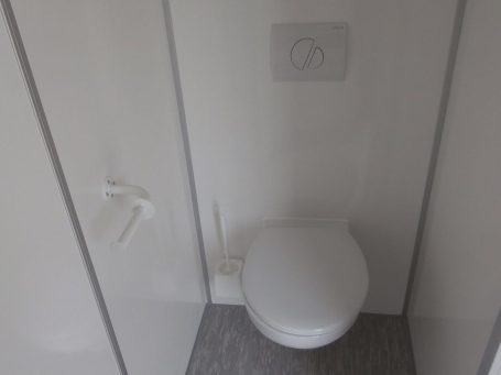 Weißes WC in einem modernen, minimalistischen Badezimmer.